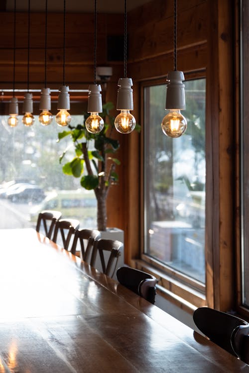 Free Light Bulbs Hanging over Long Wooden Table Stock Photo
