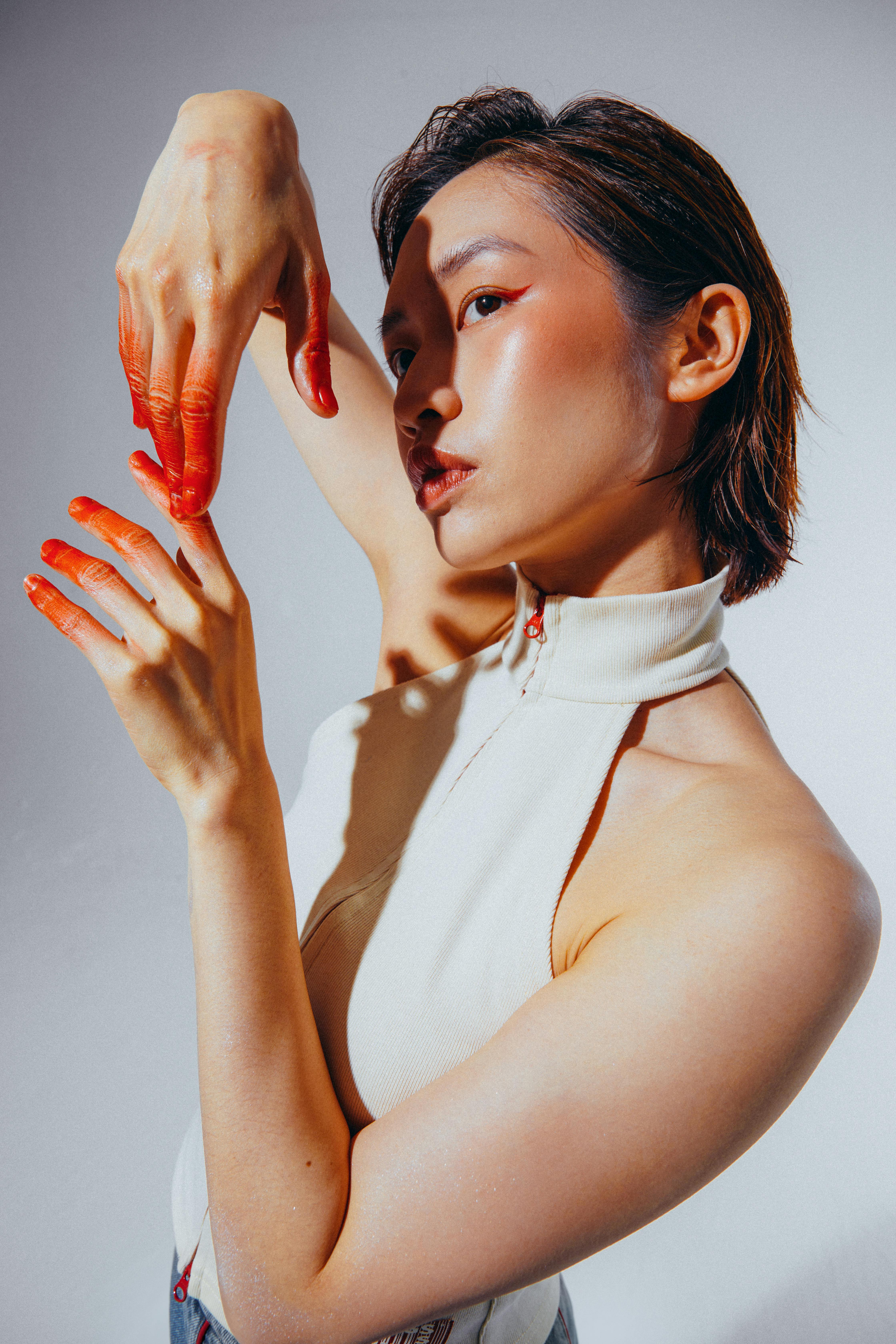 A fashionable model with painted hands posing gracefully in a studio setting.