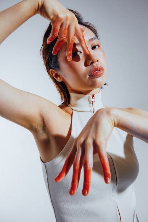 Asian Woman with Red Paint on Fingers in Studio