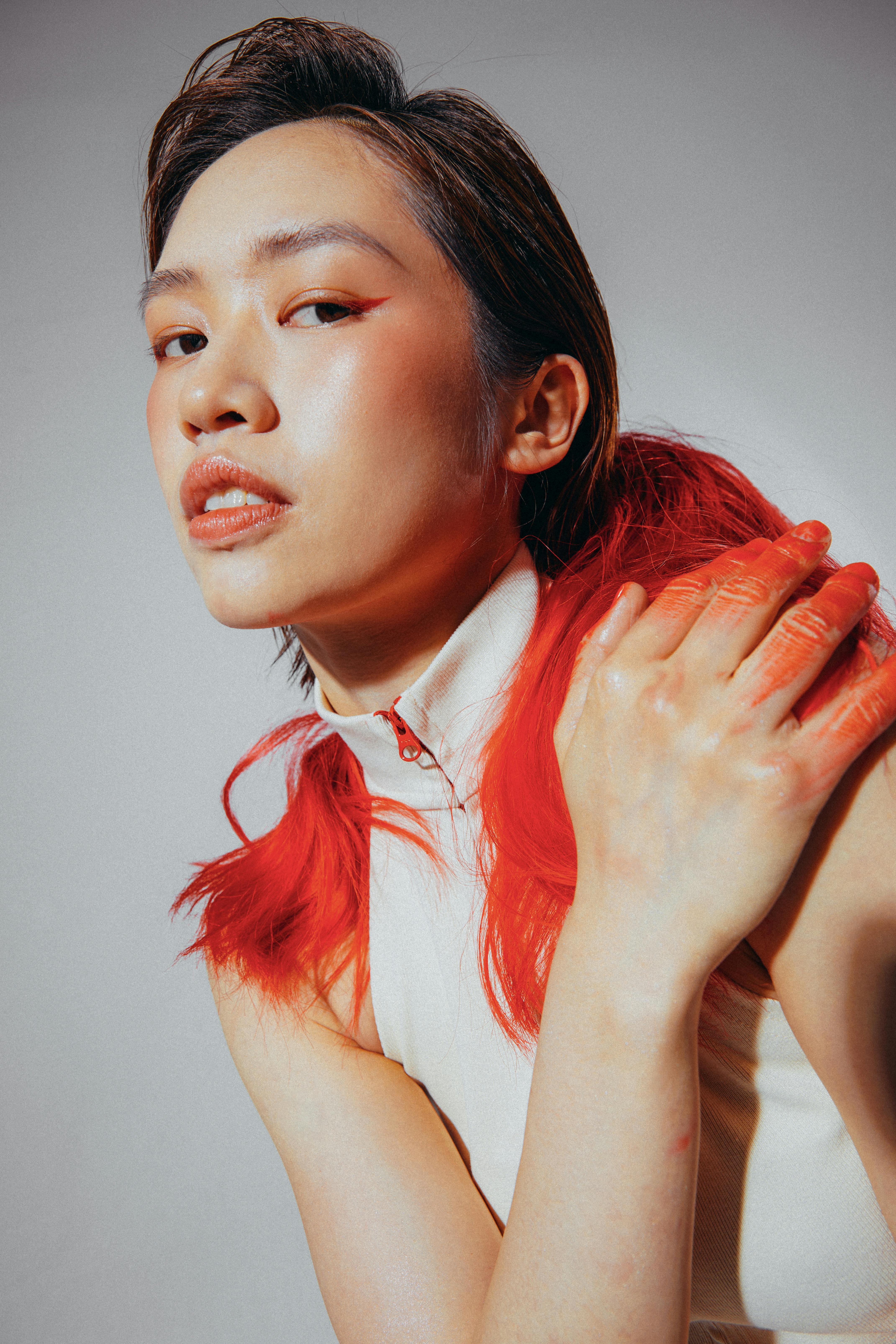 Free Artistic portrait of a woman with red-toned hair and bold makeup, against a neutral background. Stock Photo