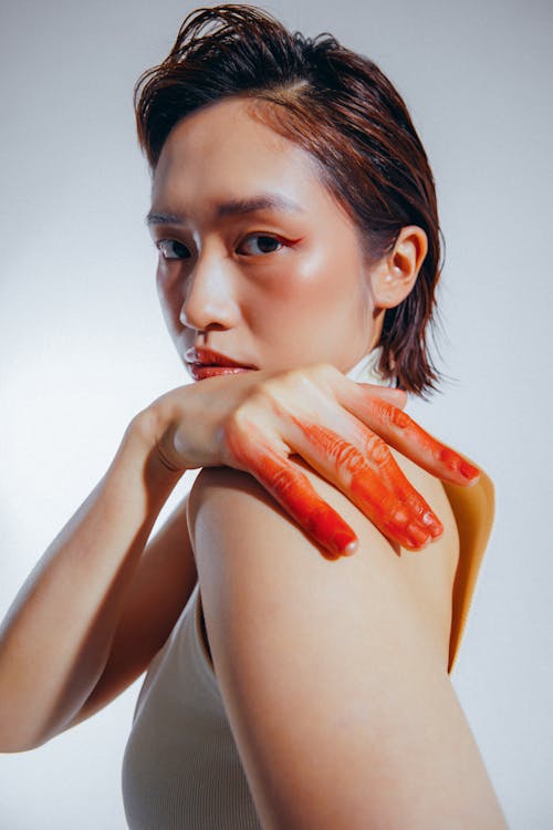 Asian Woman with Fingers in Red Paint Posing in Studio