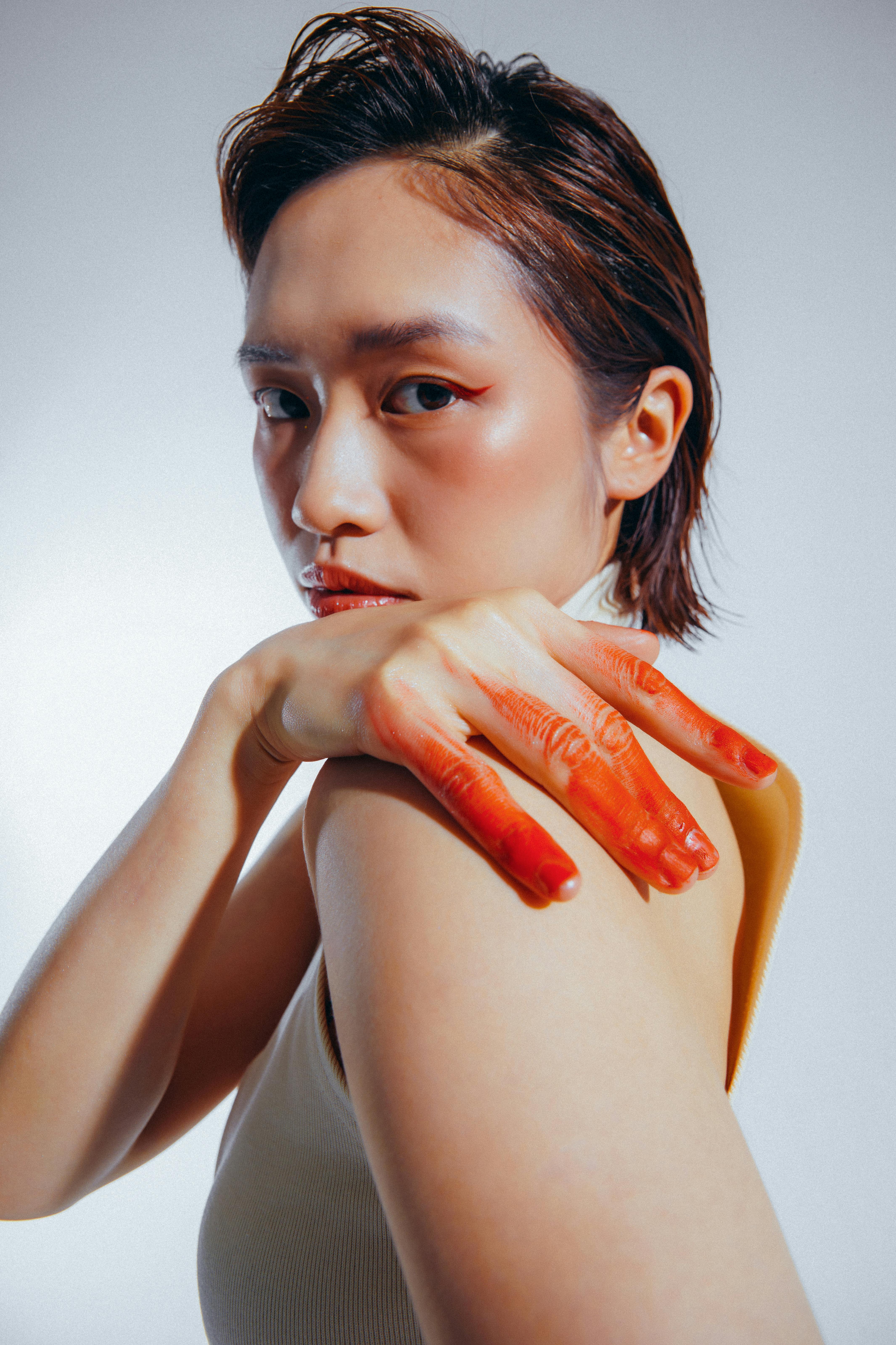 Free A striking studio portrait of a woman with a painted hand, showcasing bold fashion and style. Stock Photo