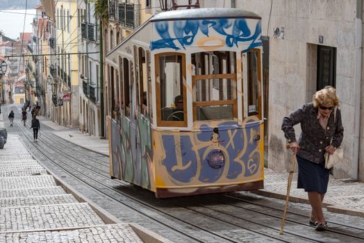 A vibrant tram on a cobblestone street in Lisbon, Portugal, with pedestrians and a scenic cityscape.