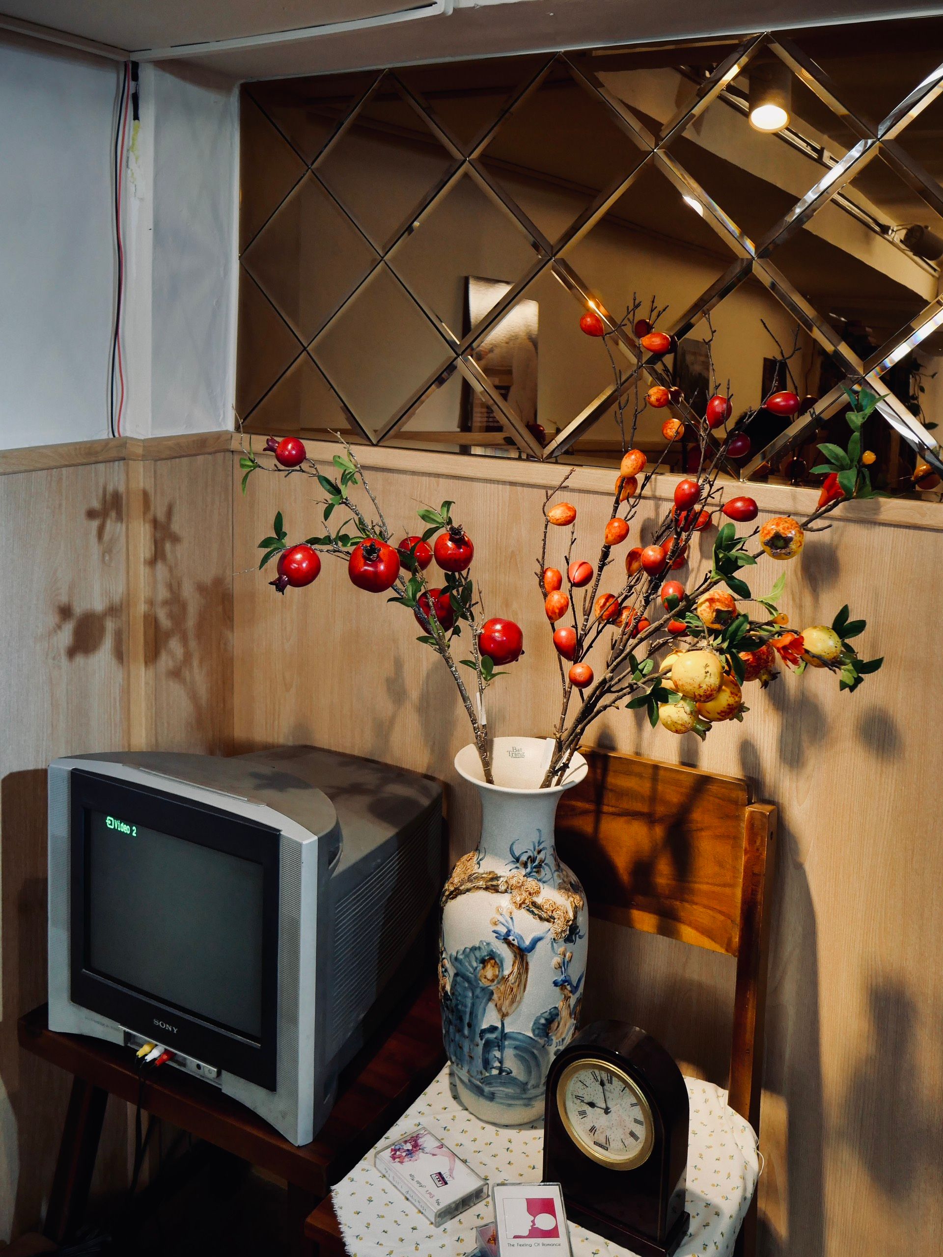A cozy corner featuring a retro TV, floral decorated vase, and vintage decor elements.