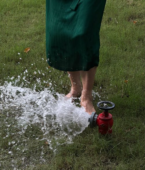 A Woman Washing Her Feet in the Water Flowing from the Fire Hydrant