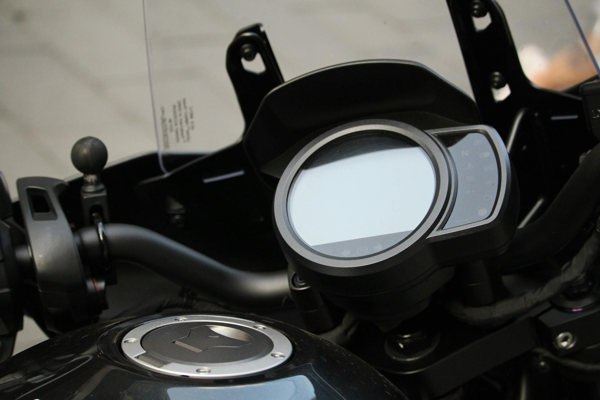 Close-up view of a motorcycle dashboard with visible handlebar and fuel tank.