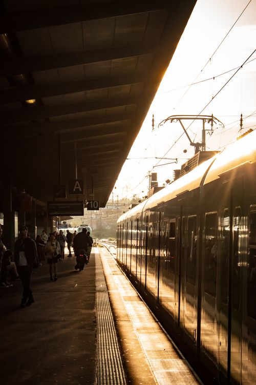Free Sunlit train platform in Essen, Germany during morning commute with travelers boarding. Stock Photo