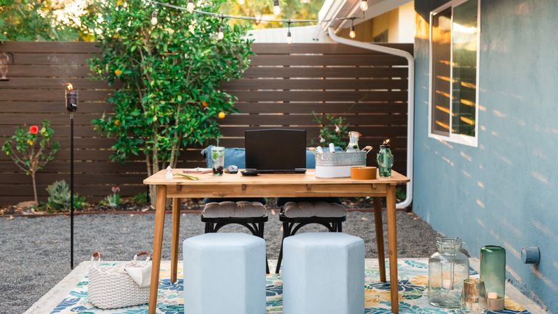 A desk and two stools set up on a garden patio
