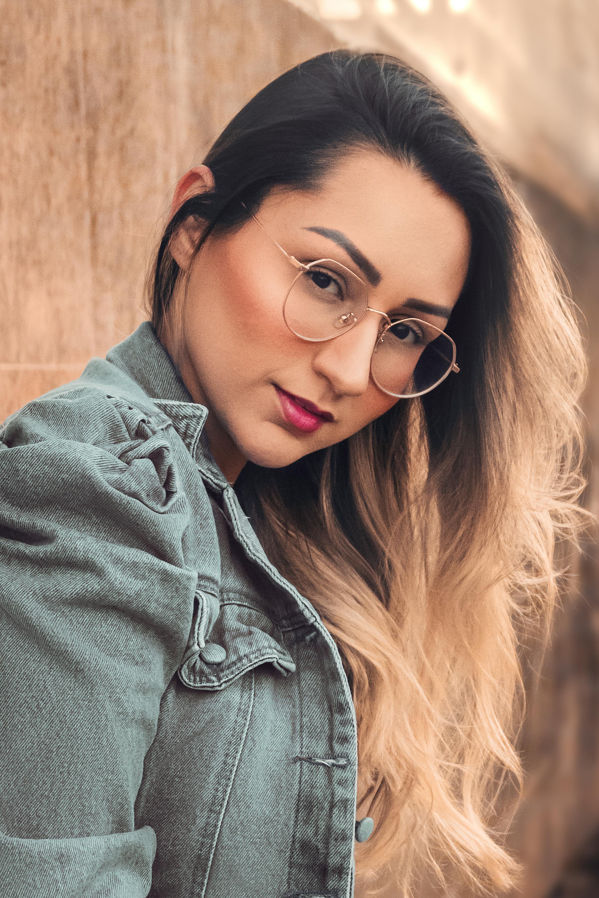 portrait of woman in glasses posing near wall