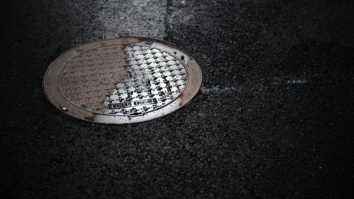 雨に濡れた路面にはめ込まれたマンホールのふた