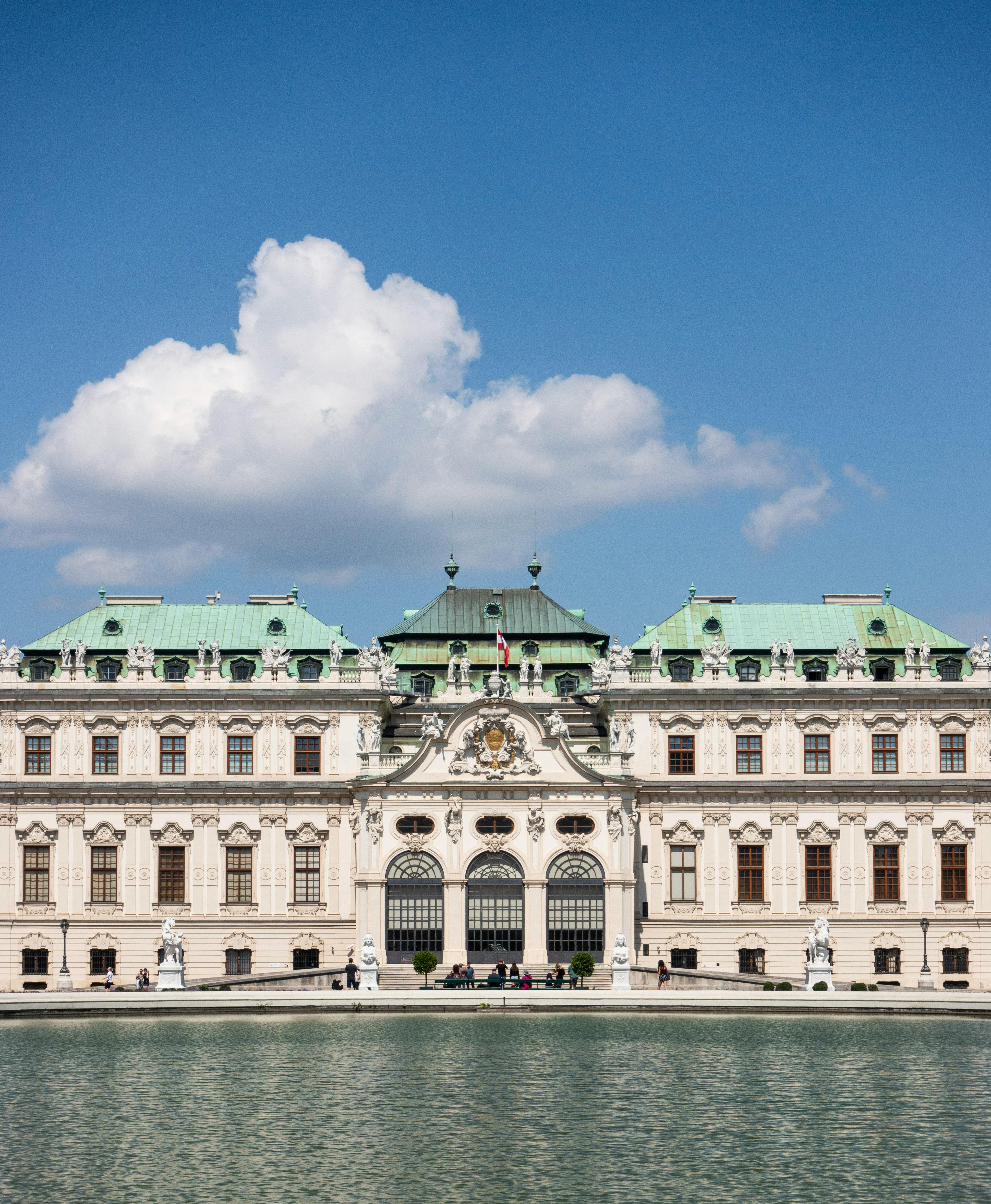 Elegant view of Belvedere Palace, Vienna with blue skies and reflecting pond.