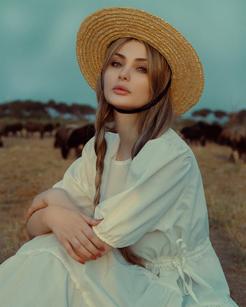 Woman in White Dress and Straw Hat in Pasture