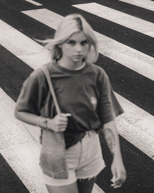 Blonde Woman with Mesh Bag on Shoulders Walking on Crosswalk