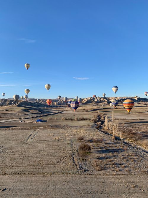 Free Scenic aerial view of hot air balloons floating over Cappadocia's unique rock formations at sunrise. Stock Photo