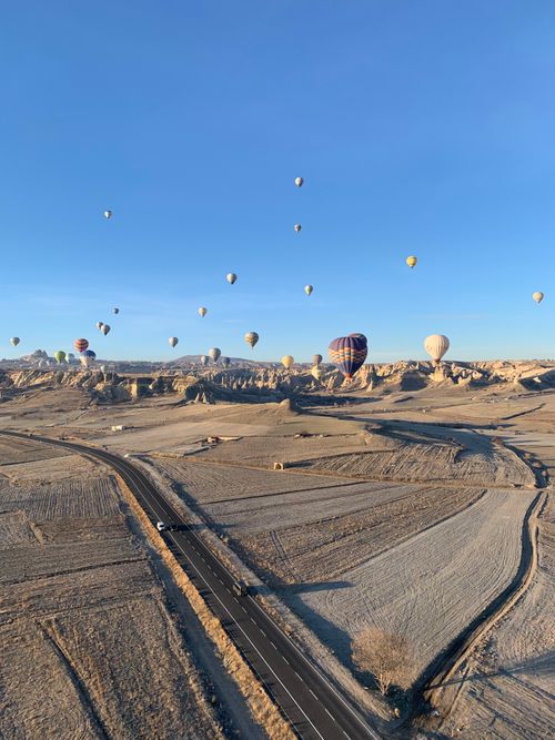 Free A stunning view of hot air balloons floating over the rocky terrain of Cappadocia, Turkey. Stock Photo