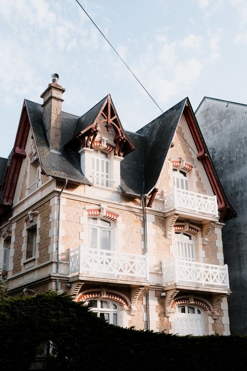 Free Elegant old house with decorative balconies under a bright sky, showcasing classic architectural style. Stock Photo