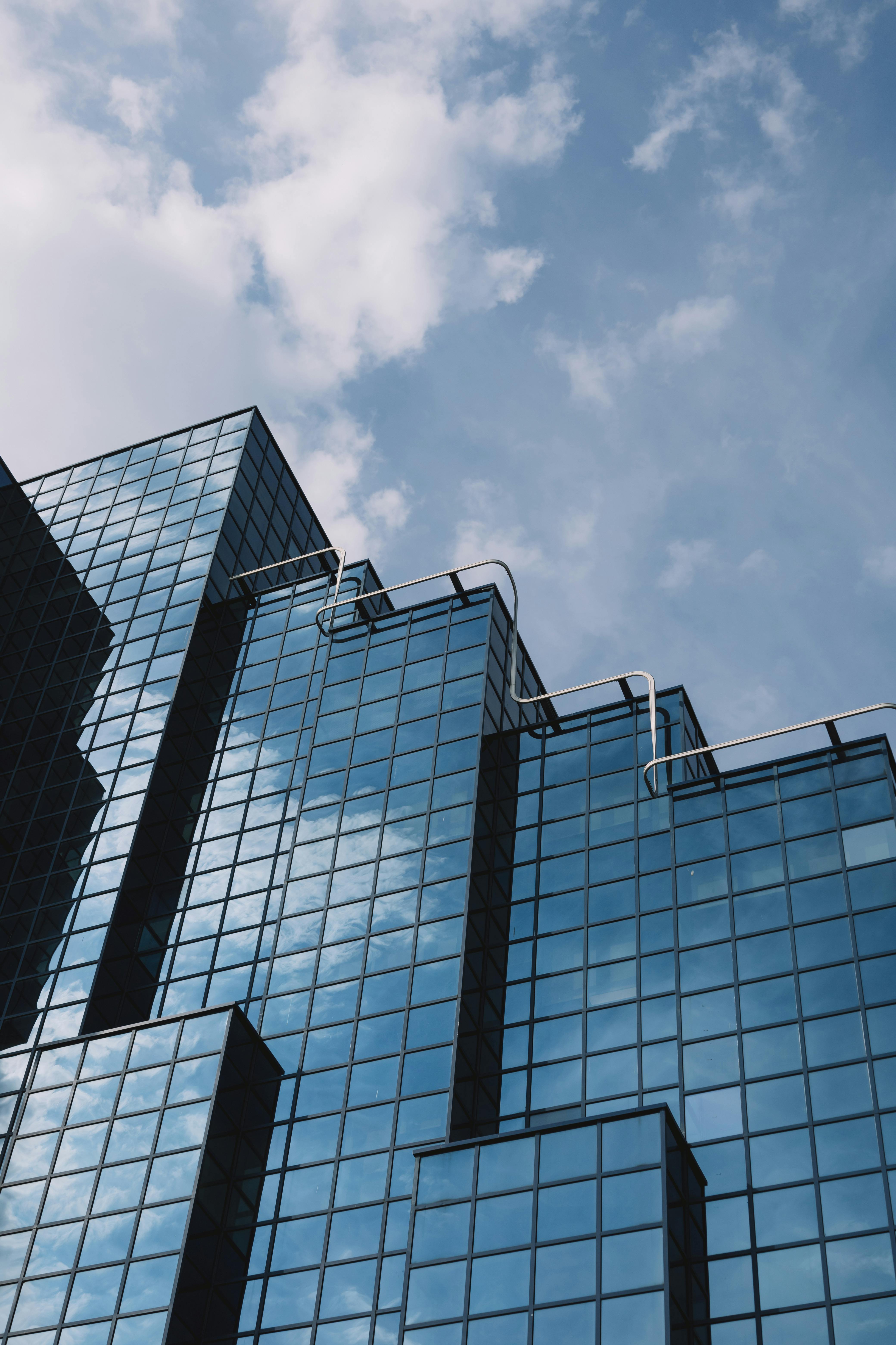 Low angle view of a modern glass office building in London's financial district on a clear day.