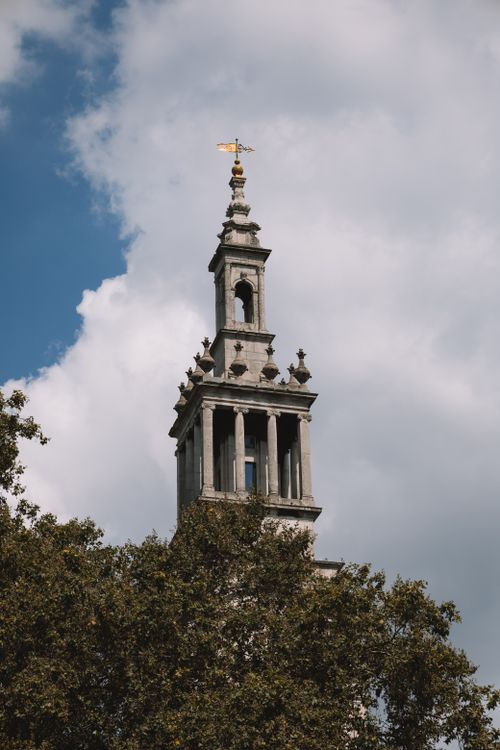 Free A striking view of a historic tower in London framed by clouds and greenery. Stock Photo