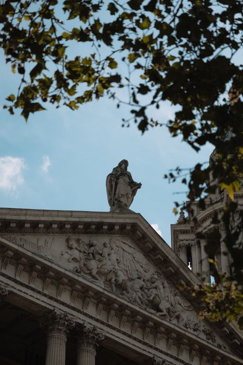 Free View of a statue atop St. Paul's Cathedral framed by leaves on a sunny day. Stock Photo