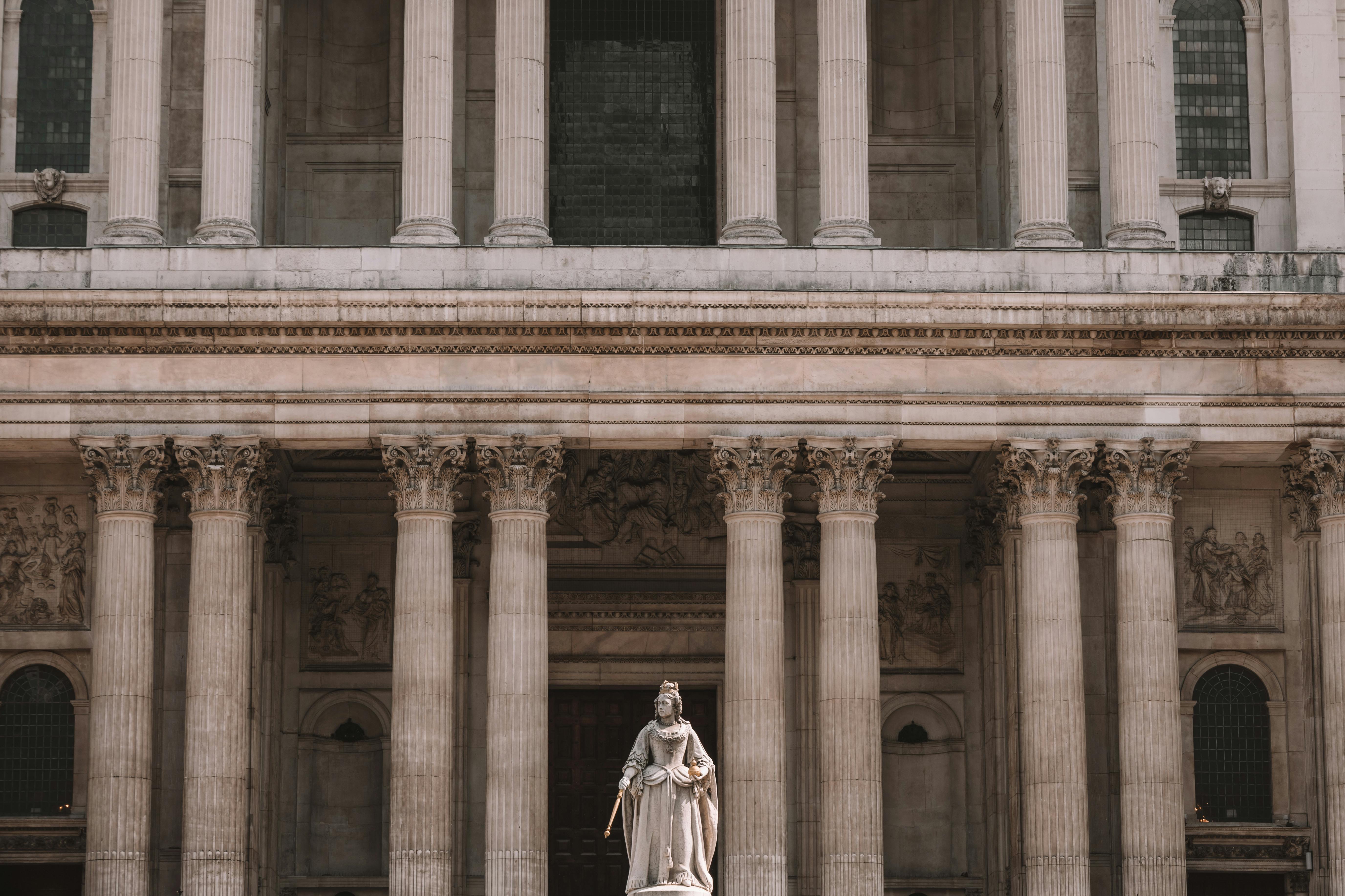 View of St. Paul's Cathedral facade with Queen Anne statue in London, England.