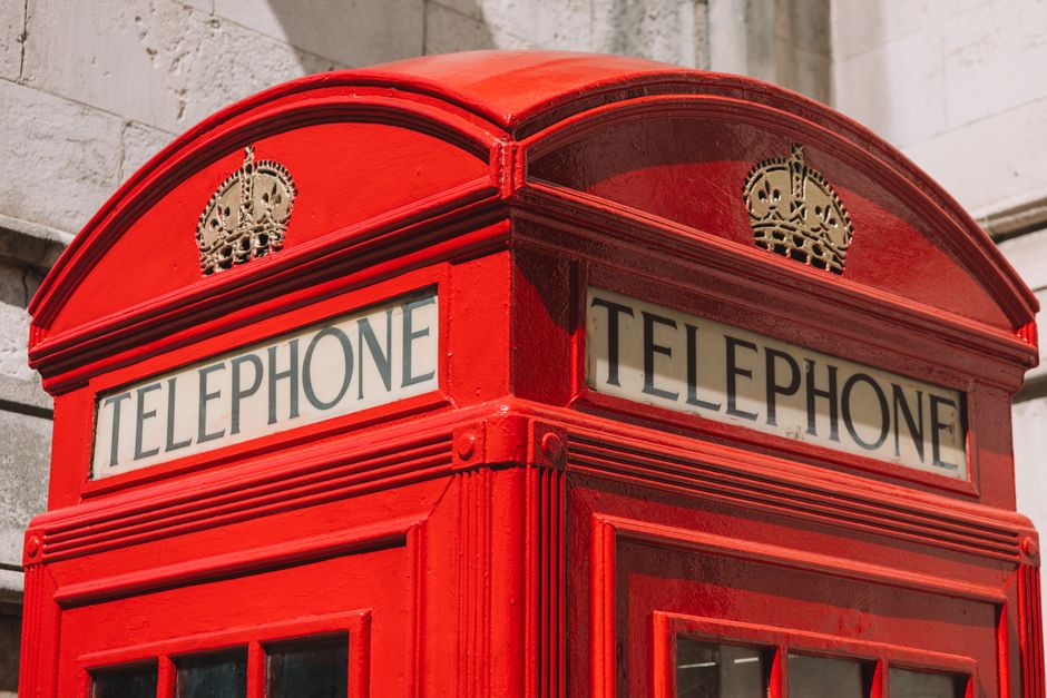 Classic red telephone booth on a street in London, England, symbolizing British tradition.