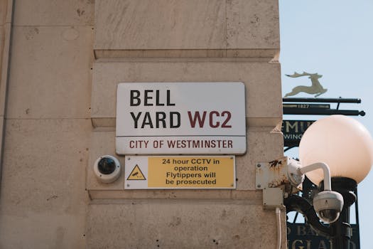 Close-up of Bell Yard street sign and CCTV notice in Westminster, London.