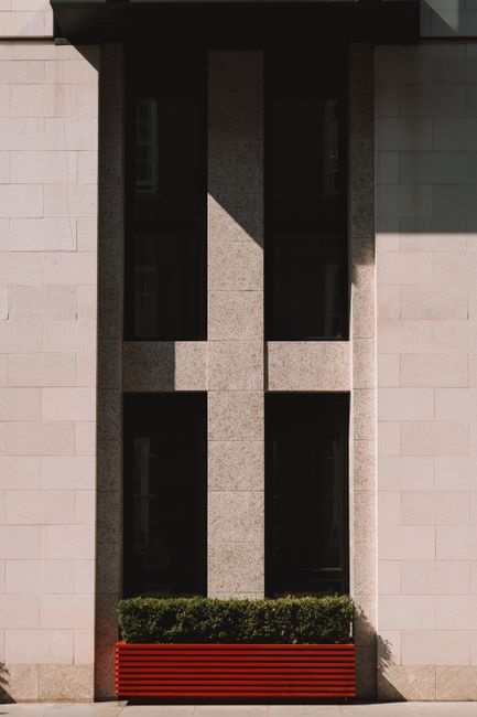 Close-up of a modern building's facade featuring rectangular windows and greenery.