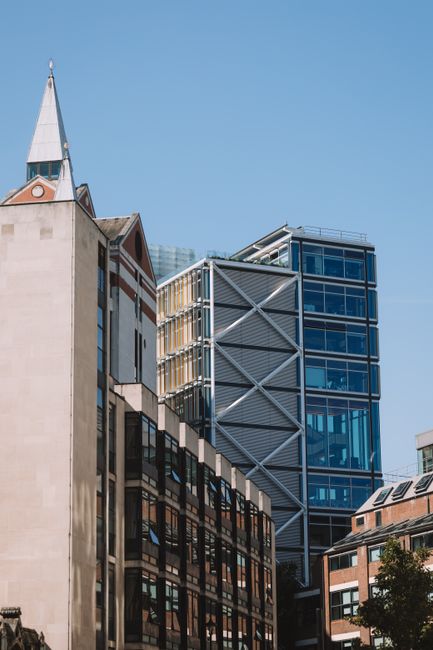 A mix of modern and classic architecture under a clear blue sky in an urban cityscape.