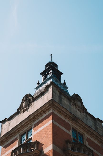 A low-angle shot of a historic brick tower with intricate details against a clear blue sky.