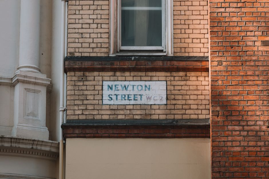 Close-up of Newton Street sign on a brick facade in London, capturing urban architectural details.