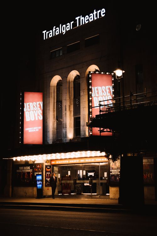 Free Night view of Trafalgar Theatre in London with Jersey Boys display, illuminated facade. Stock Photo