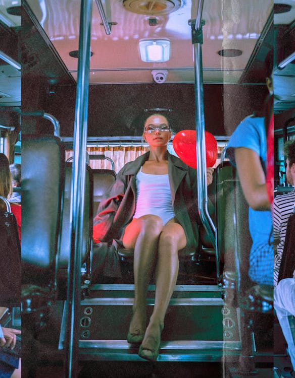 Woman Sitting in a Bus Holding a Heart Shaped Balloon