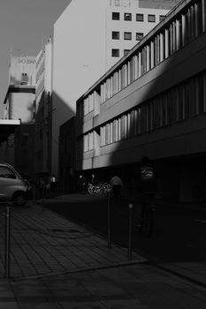 Black and white photo capturing modernist architecture and city life with strong shadows.