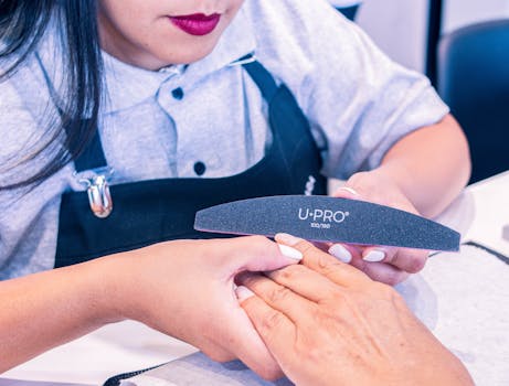 A professional nail technician provides a manicure service in a beauty salon, focusing on nail care.