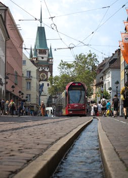 Tram in Freiburg im Breisgau, Germany, travels through a historic street lined with buildings and tourists.