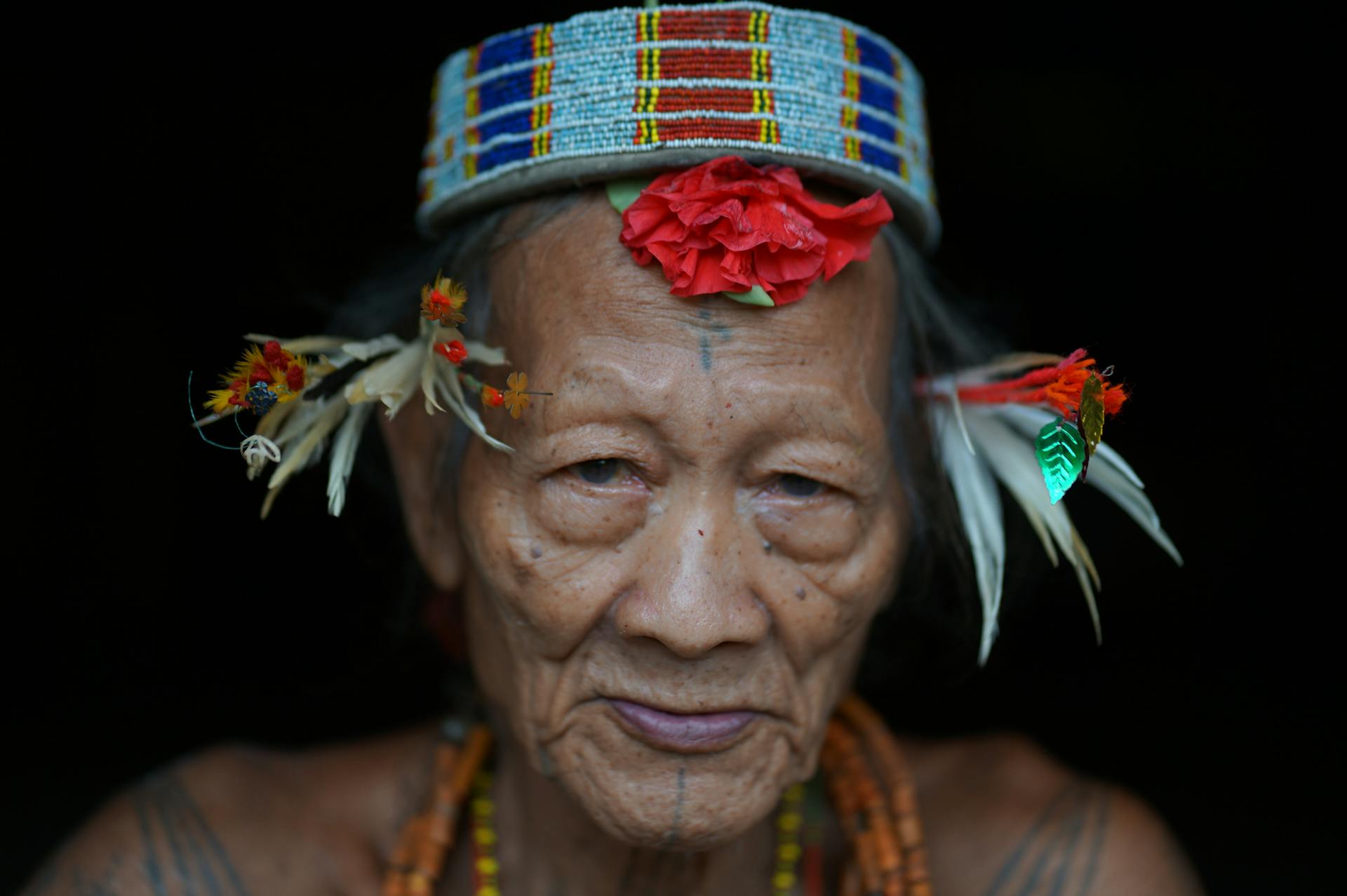 Elderly tribal man with traditional headdress and tattoos from West Sumatra, Indonesia.