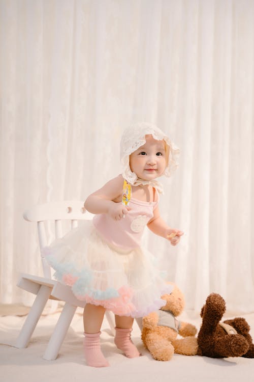 Baby in Bonnet Hat Sitting on Wooden Chair