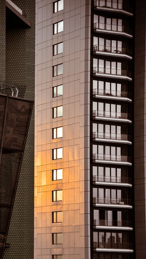Free Warm sunlight reflects on a modern high-rise building's sleek facade at sunset. Stock Photo