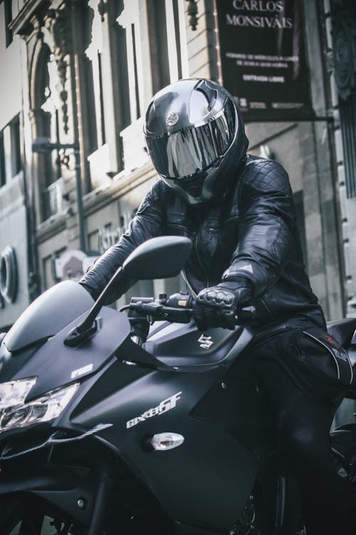 Man in Leather Jacket and Helmet Sitting on Black Motorcycle