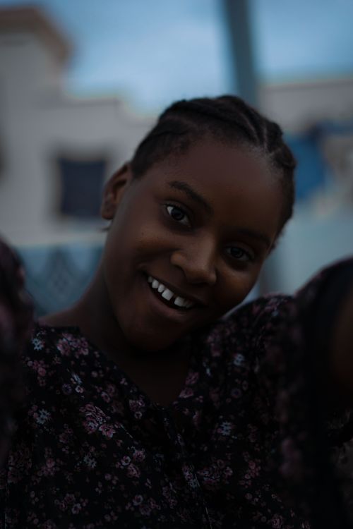 Free Portrait of a young woman with a joyful smile and braided hair outdoors in Senegal. Stock Photo