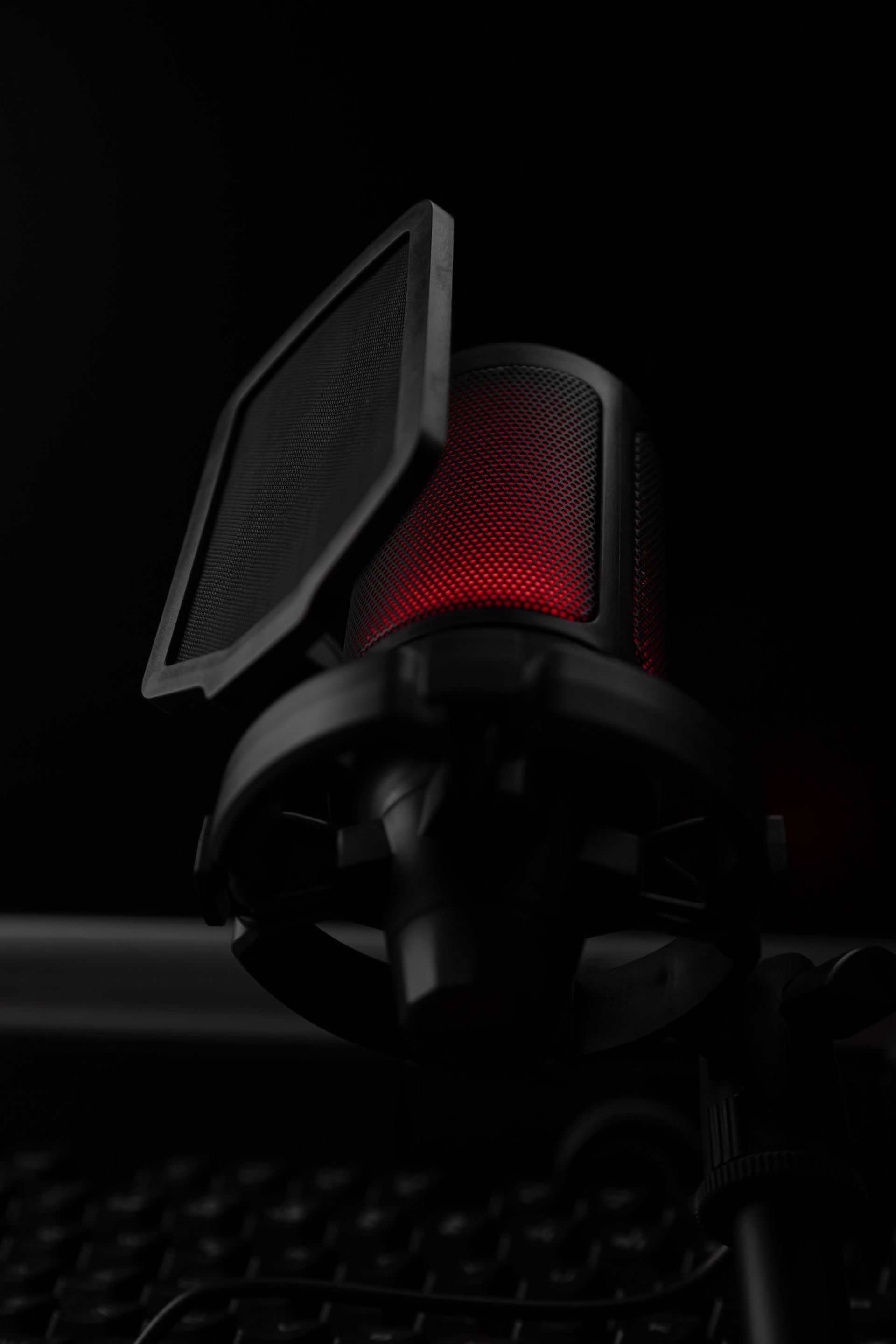 Micrófono de estudio con luz roja sobre fondo oscuro