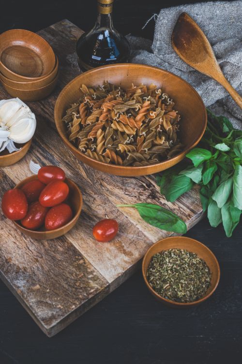 Free Top-down view of rustic pasta ingredients on a wooden board, ready to cook. Stock Photo