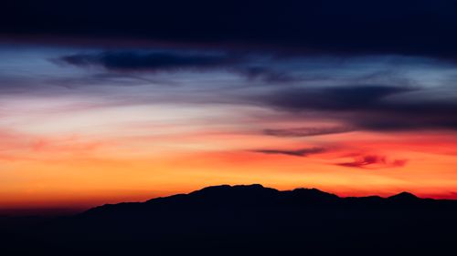 Free Captivating mountain silhouette against a vivid sunset sky with striking color contrast. Stock Photo