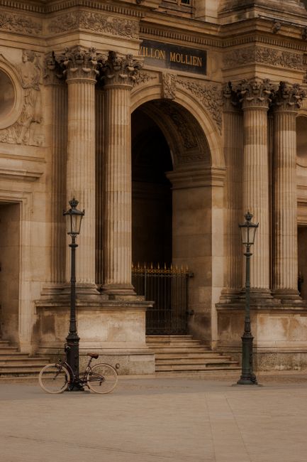 Classic architectural facade of the Louvre Museum in Paris with a vintage bike.