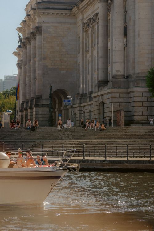 Free People enjoying a sunny day on a boat in Berlin, Germany, with a historical building in the backdrop. Stock Photo
