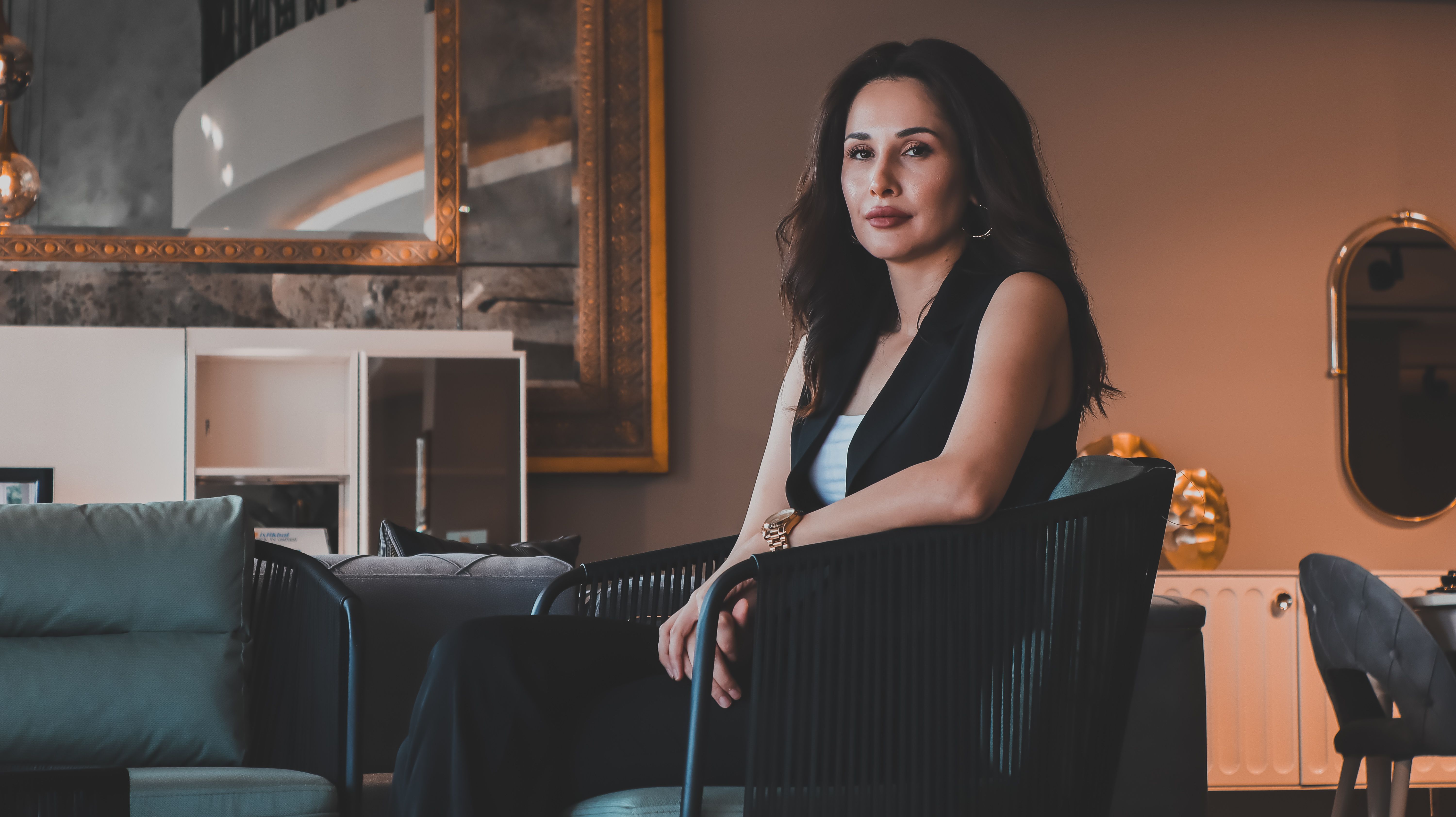 A woman sits confidently in a modern living room interior, exuding elegance and style.