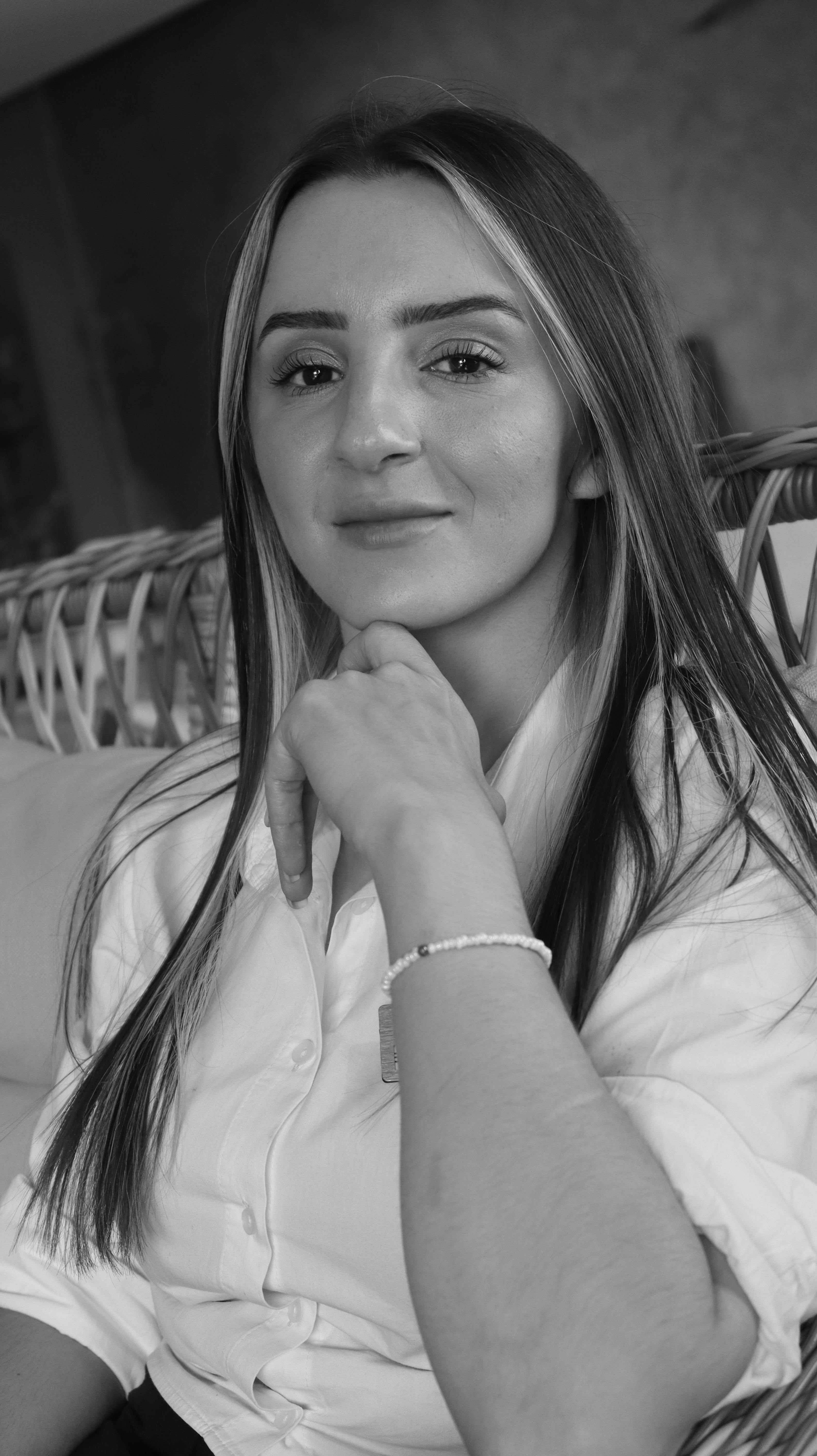 Black and white portrait of a woman with long hair and a confident pose indoors.