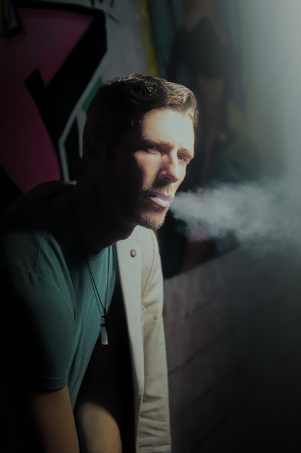 Fotomural Un retrato dramático de un hombre exhalando humo contra un fondo de graffiti en Ciudad de México.