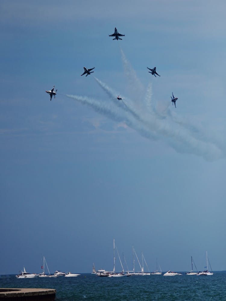 Military Jets Flying Above Boats In The Sea