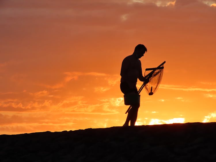 Man Holding Hand Net At Dusk